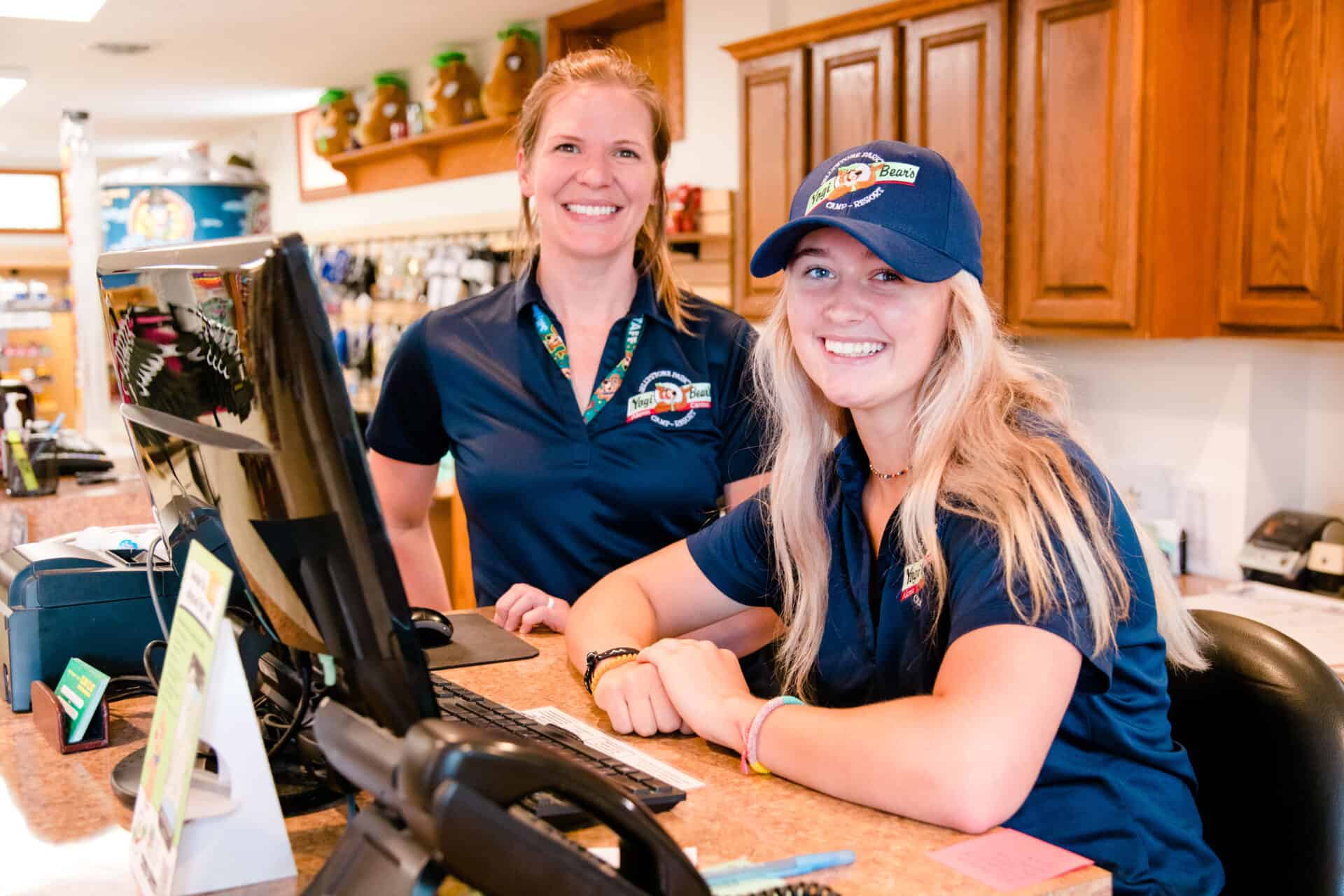 Two women smiling at the counter of a store, enjoying the amenities.