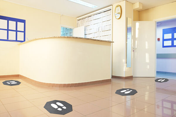 Stick and Stand in place front desk 900x600 1 Floormat.com Stick-and-Stand mats are adhesive-backed social distancing mats designed to mark a safe place for customers to stand while waiting in lines. <strong>Sold by case only, with 6 mats per case.</strong> <ul> <li>Universal "stop sign" shape with shoe prints marks where customers should stand; mats can be placed at safe intervals in virtually any configuration.</li> <li>Adhesive backing keeps the mat flat and in place, even with heavy cart and buggy traffic.</li> <li>Mats can be left in place during daily floor cleaning; floor scrubbers, mops, and brooms will pass right over them without causing damage.</li> <li>Less likely than floor decals to leave a sticky residue.</li> <li>Treated with an anti-microbial formula for protection from odors.</li> <li>Low-profile design with a high-traction surface to enhance slip resistance.</li> <li>Mat lifetime is up to 3 to 4 months under normal use.</li> </ul>